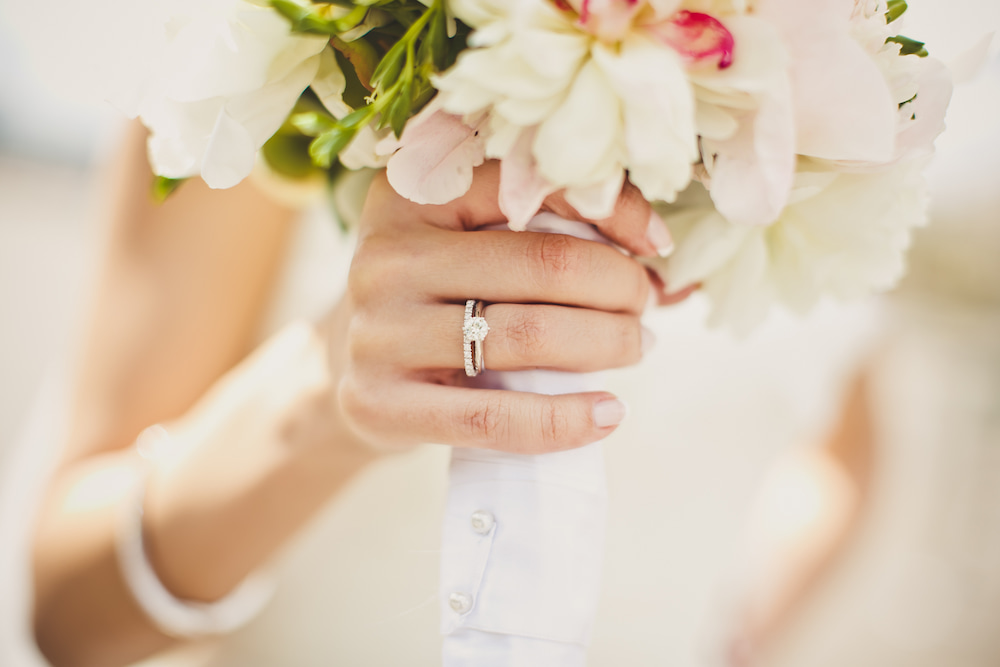 Bague de fiançailles et alliance portées ensemble sur la main d'une mariée
